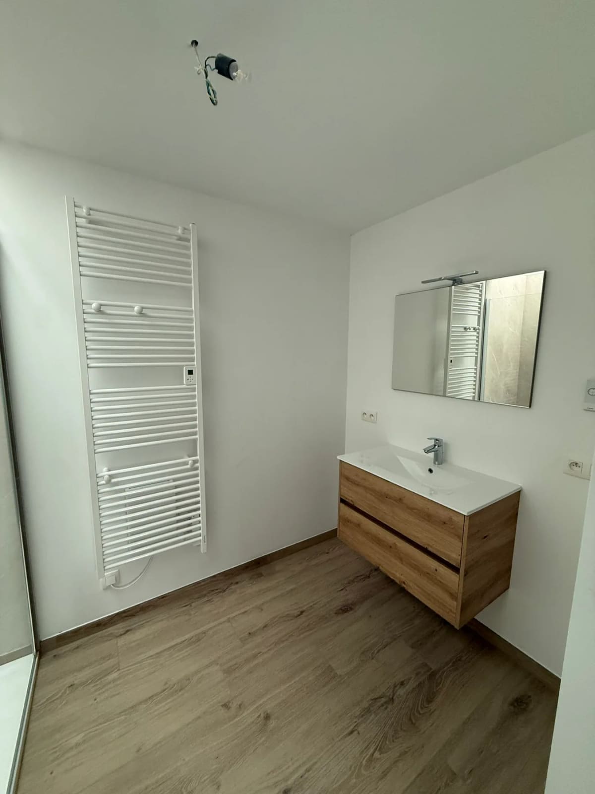 Salle de bain terminée avec douche vitrée et mobilier en bois