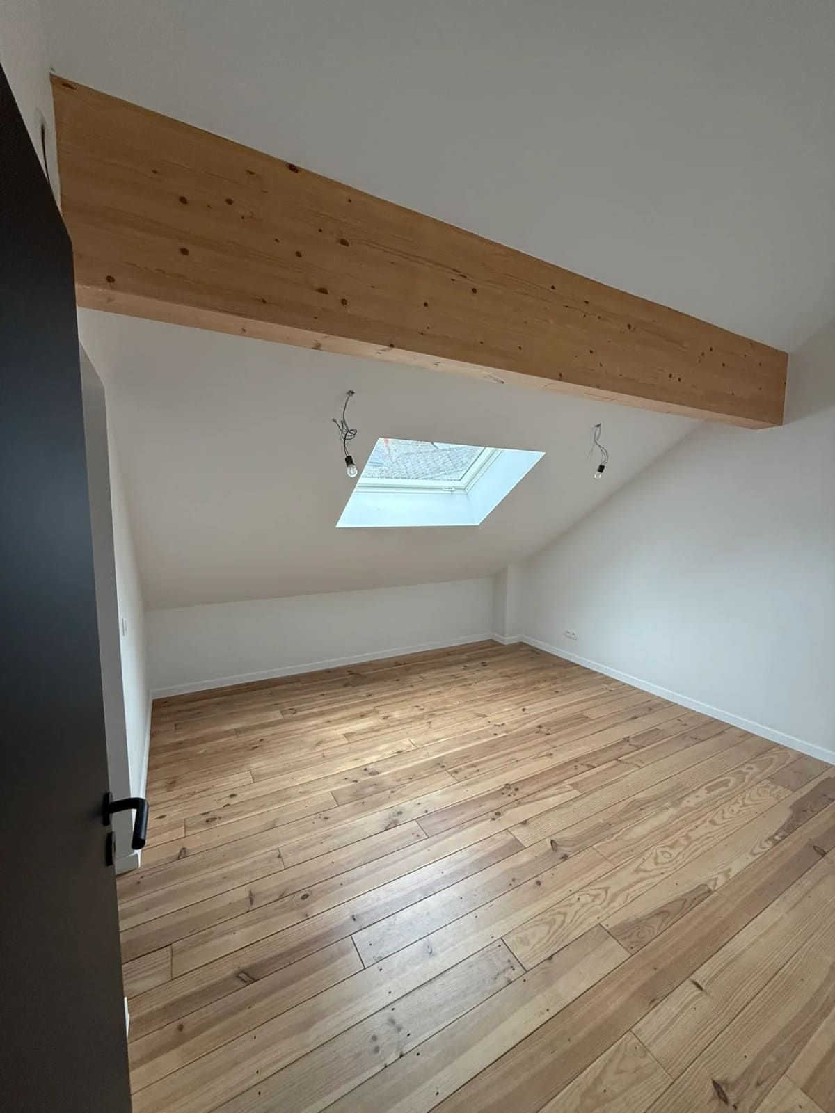 Chambre terminée sous toiture avec parquet et fenêtre de toit